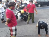 Pecalang atau pengamanan adat di Bali mengawasi warga yang tengah dihukum push up karena melanggar protokol kesehatan setelah terjaring razia - foto: Istimewa